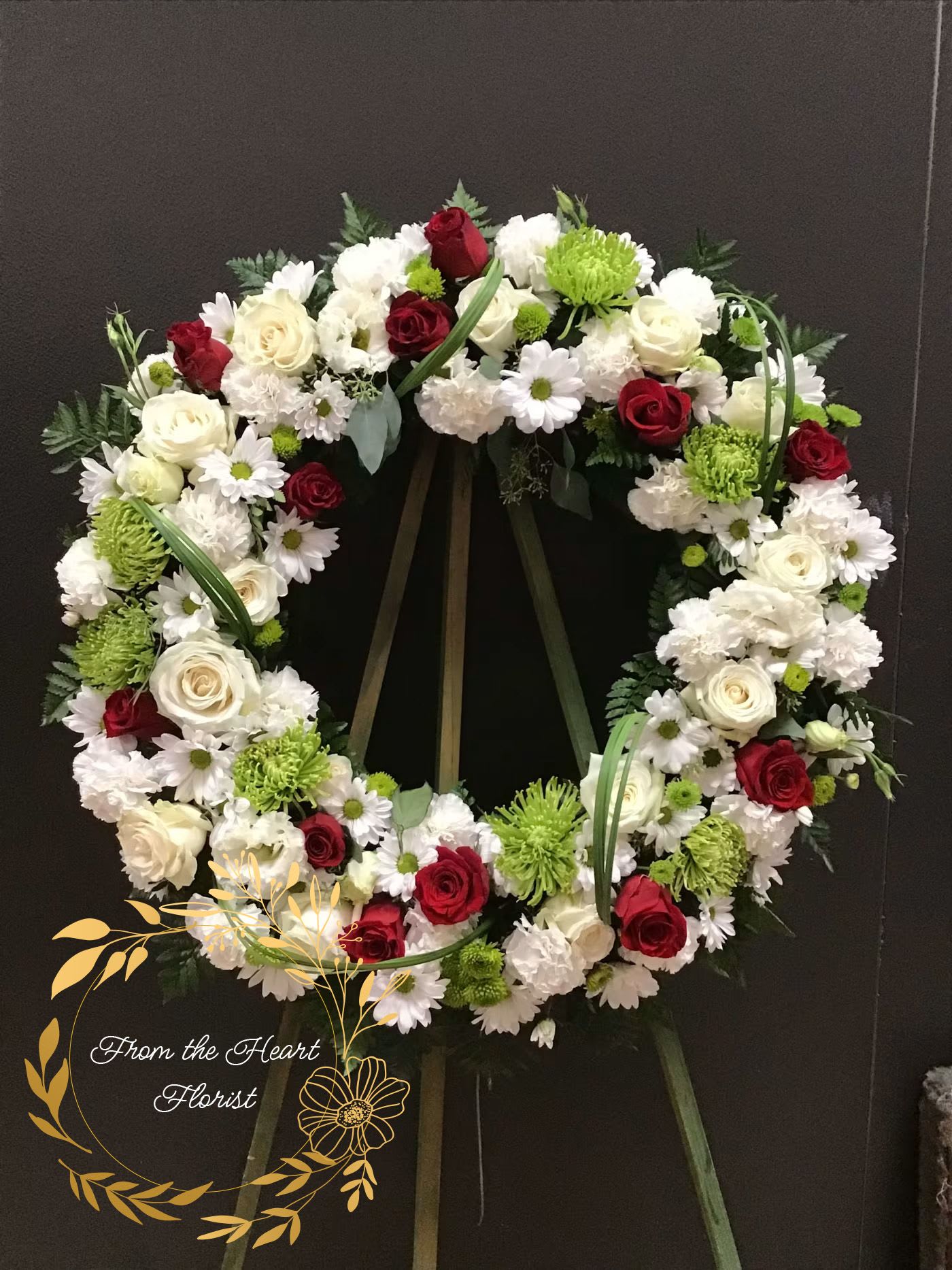 Circular funeral wreath of red and white flowers on a stand