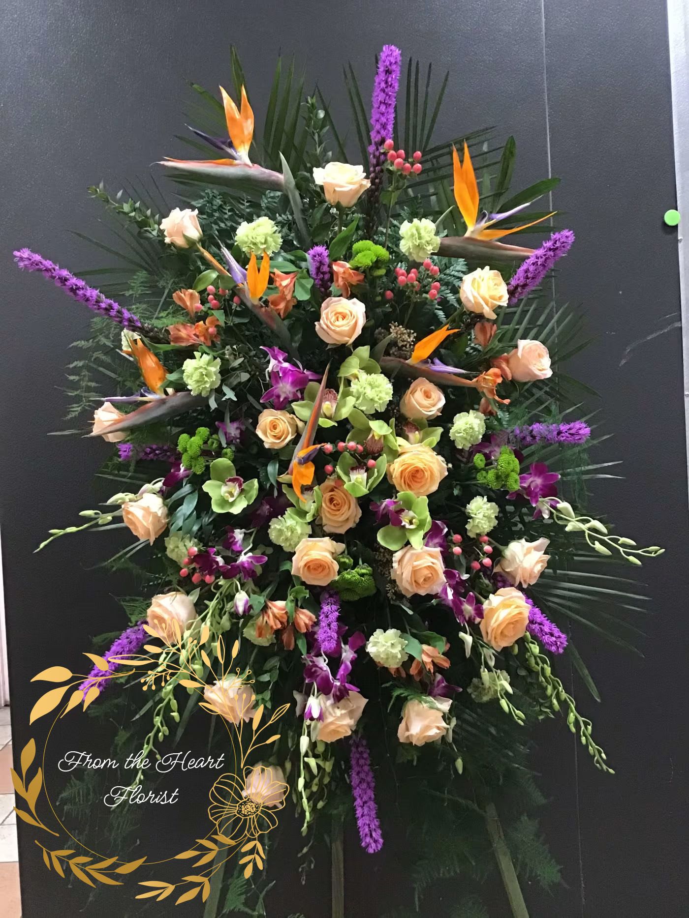 Large tropical floral spray with roses, orchids, and purple spikes