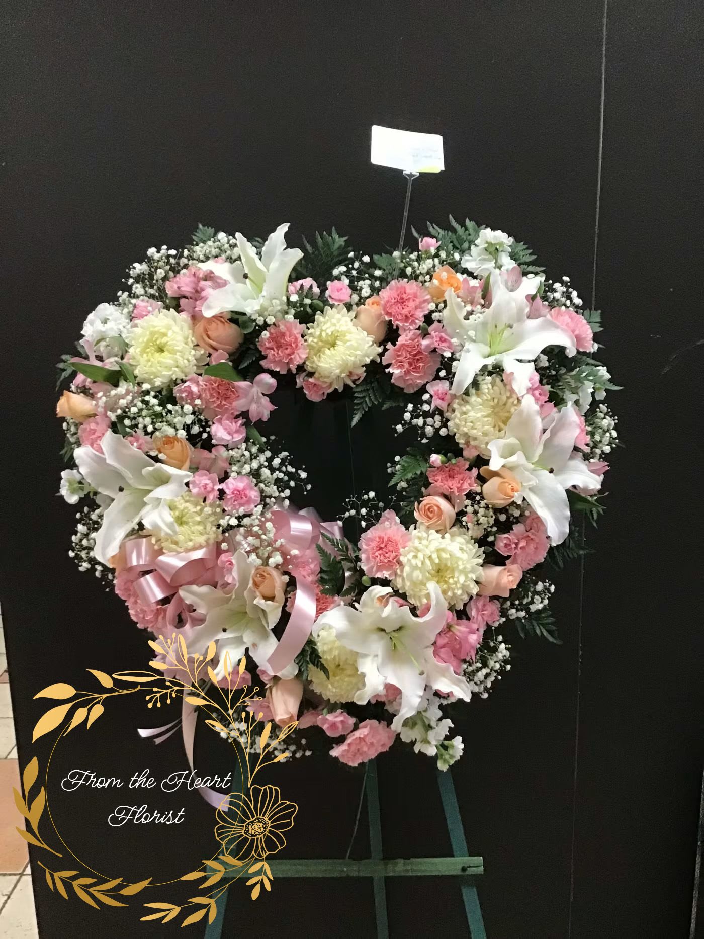 Heart-shaped floral wreath with pink and white flowers on an easel