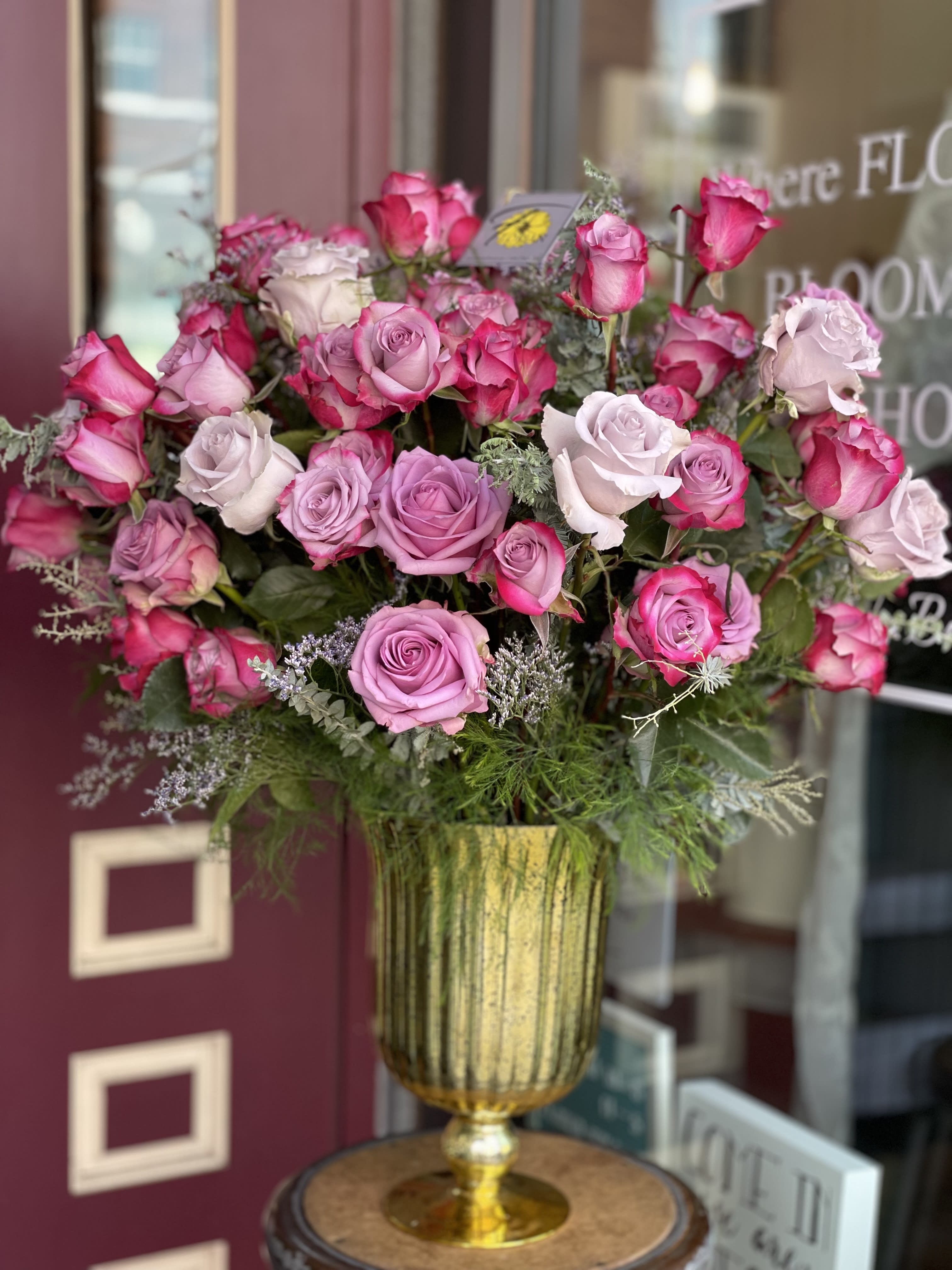Pink and lavender roses arranged in a gold vase