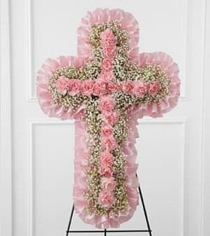 The FTD® Angel Cross™ Easel - The FTD® Angel's Cross™ Easel is a graceful tribute to honor the life and faith of the deceased. Pink mini carnations and baby's breath are lovingly arranged in the shape of a cross, accented with a pink satin ribbon around the outside and displayed on a wire easel, to create a wonderful way to express your love for the departed. Approximately 24"H x 15"W. Your purchase includes a complimentary personalized gift message.