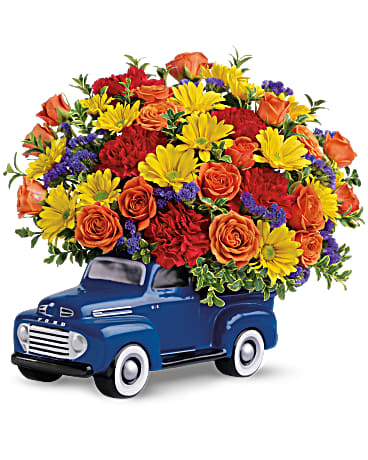 Bouquet of orange roses, yellow daisies, and red carnations in a blue truck container