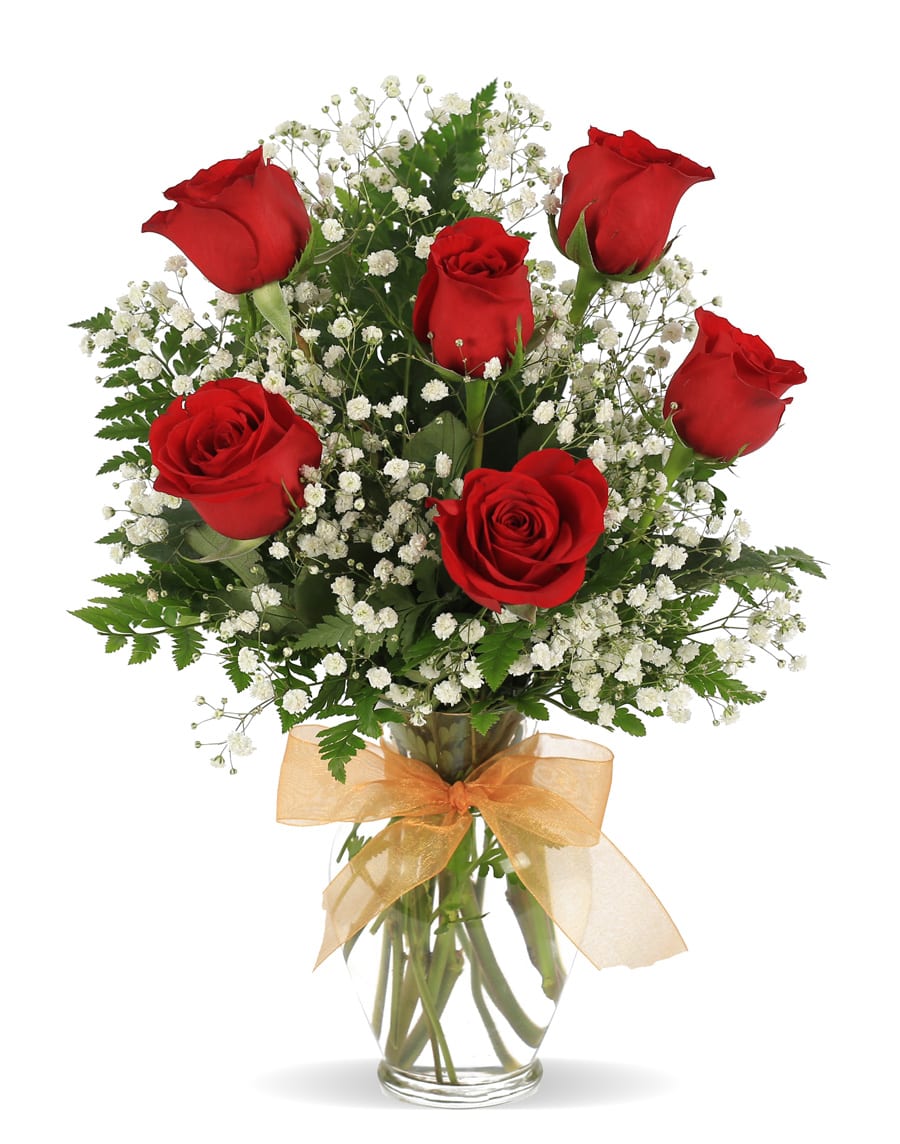 Red roses with white baby's breath in a glass vase with a gold bow