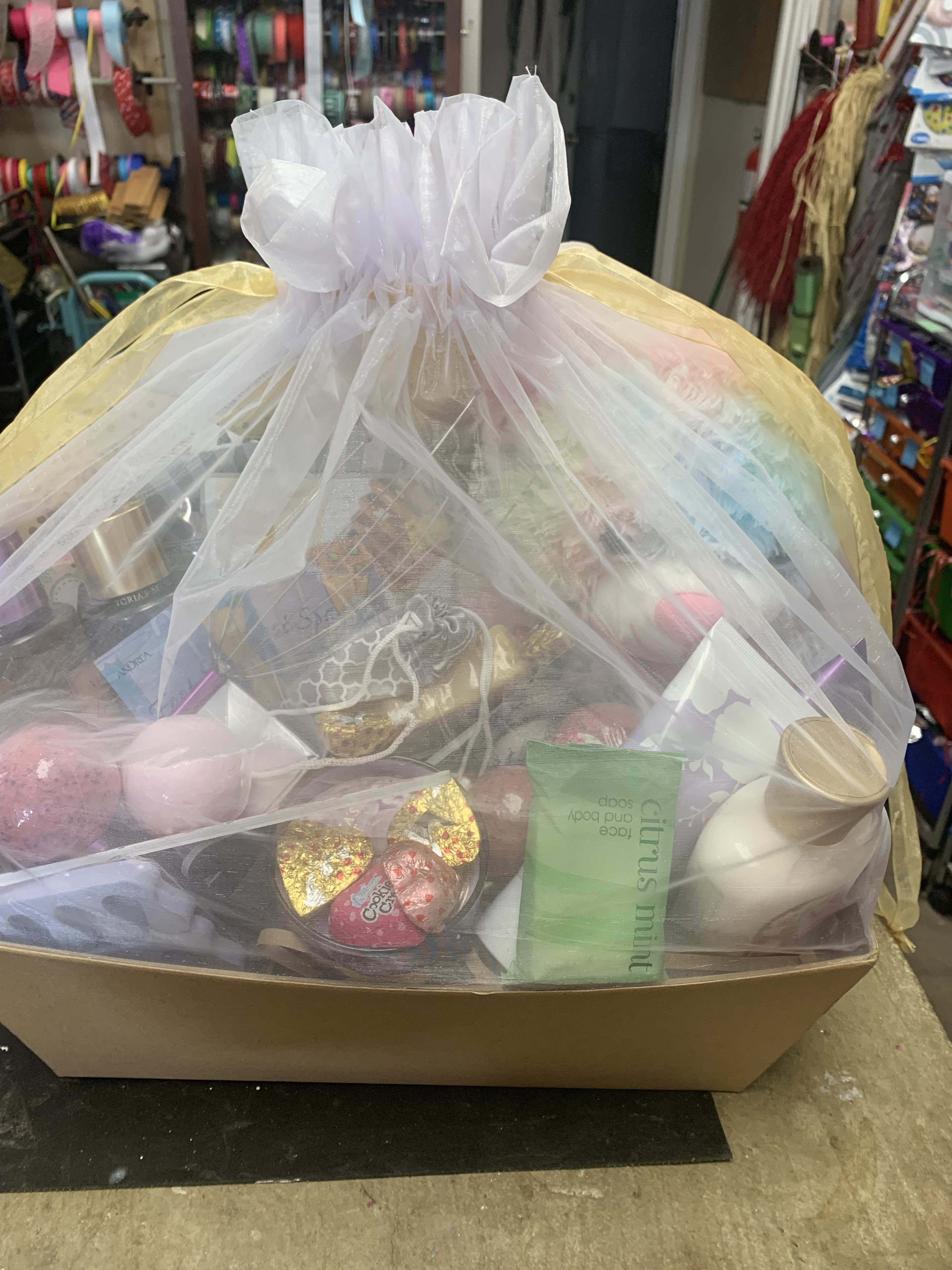 Gift basket wrapped in sheer tulle with assorted treats and candles