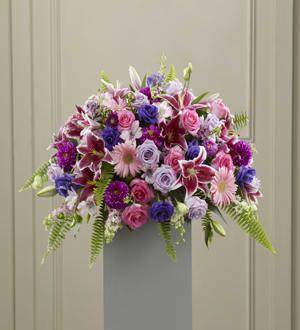 Mixed pink, purple, and white flowers arranged on a pedestal