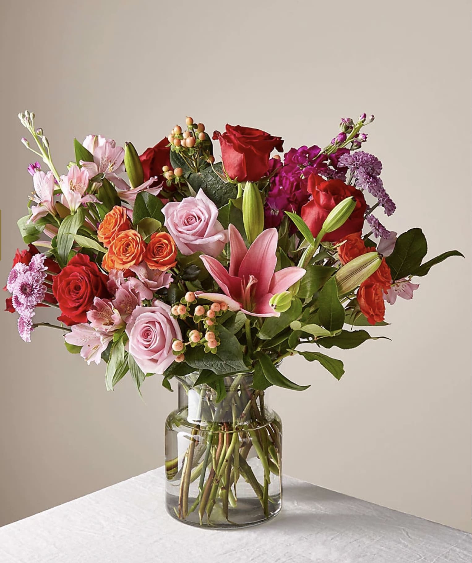 Mixed bouquet of roses, lilies, and alstroemeria in a glass vase