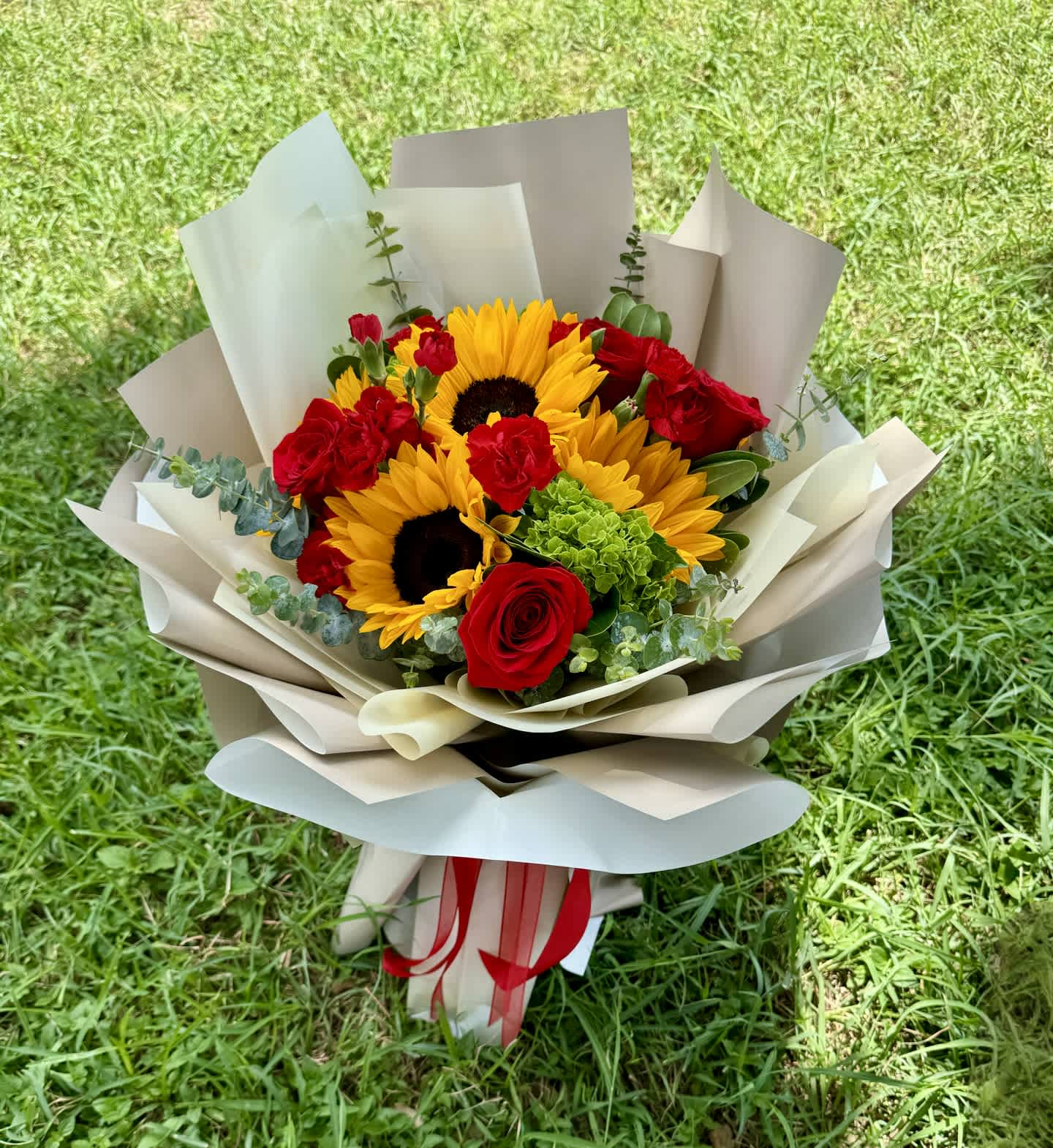 Bouquet of sunflowers and red roses wrapped in beige paper