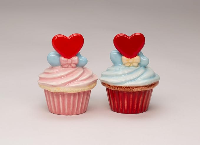 Two decorated cupcakes with heart toppers on a plain background
