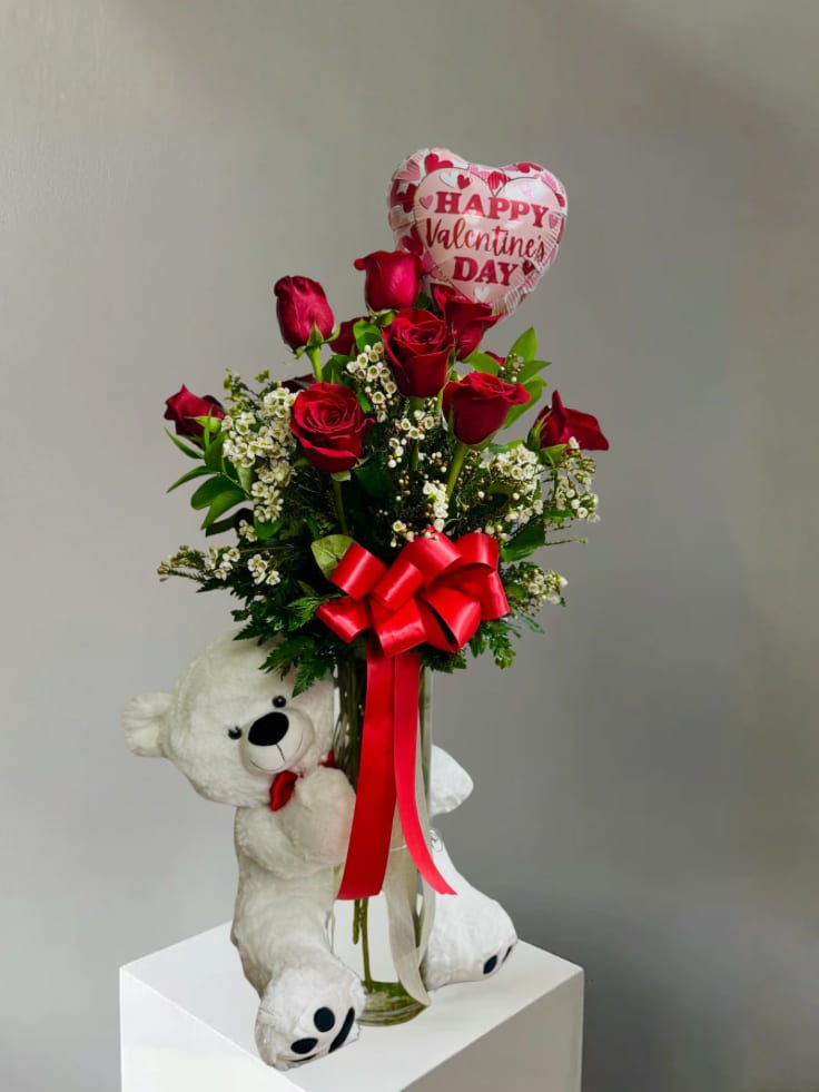 Red roses in a vase with a heart-shaped Valentine balloon and teddy bear
