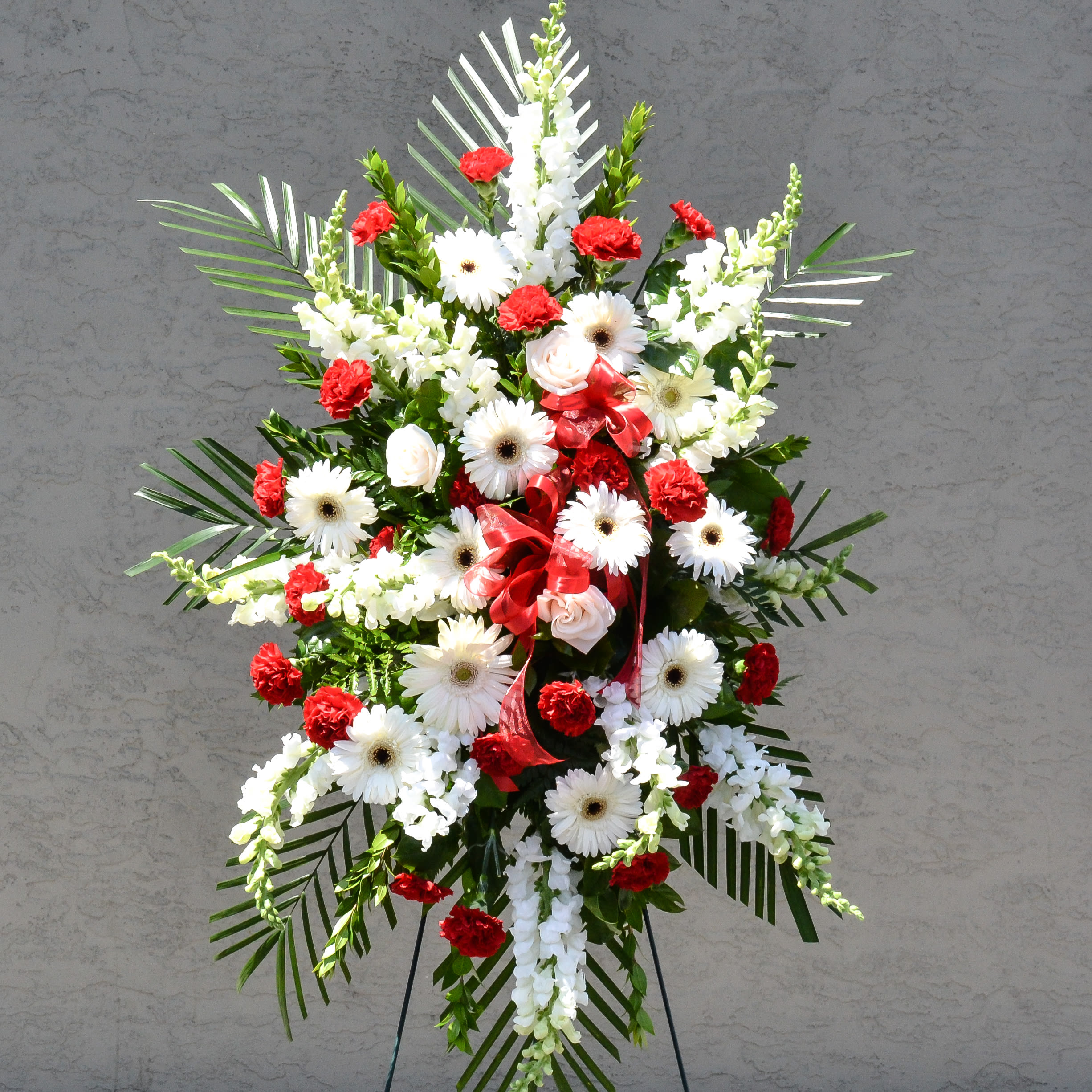 Standing floral spray with white daisies and red carnations on an easel