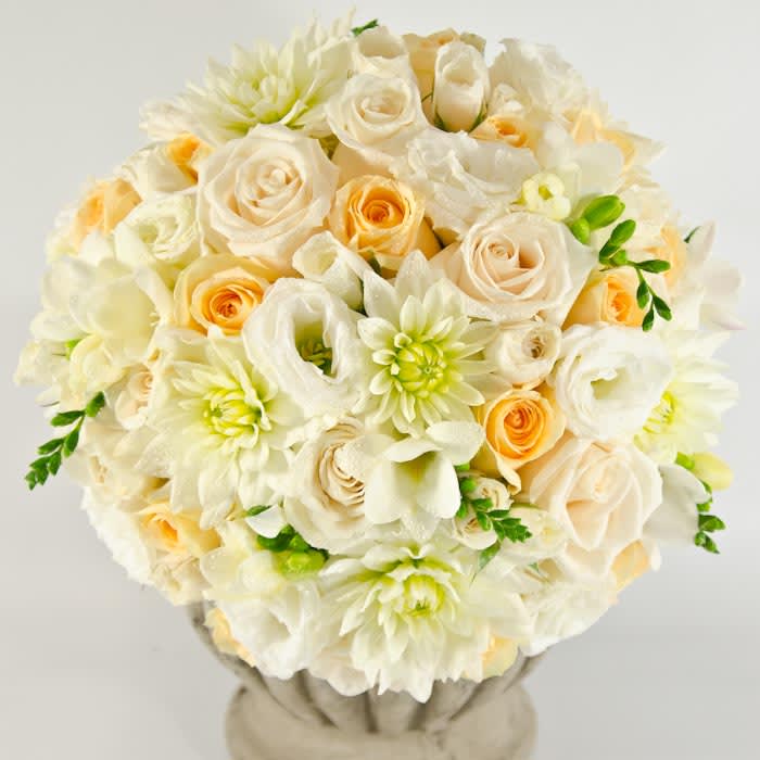 Cream and peach bouquet of roses, dahlias, and calla lilies in a vase