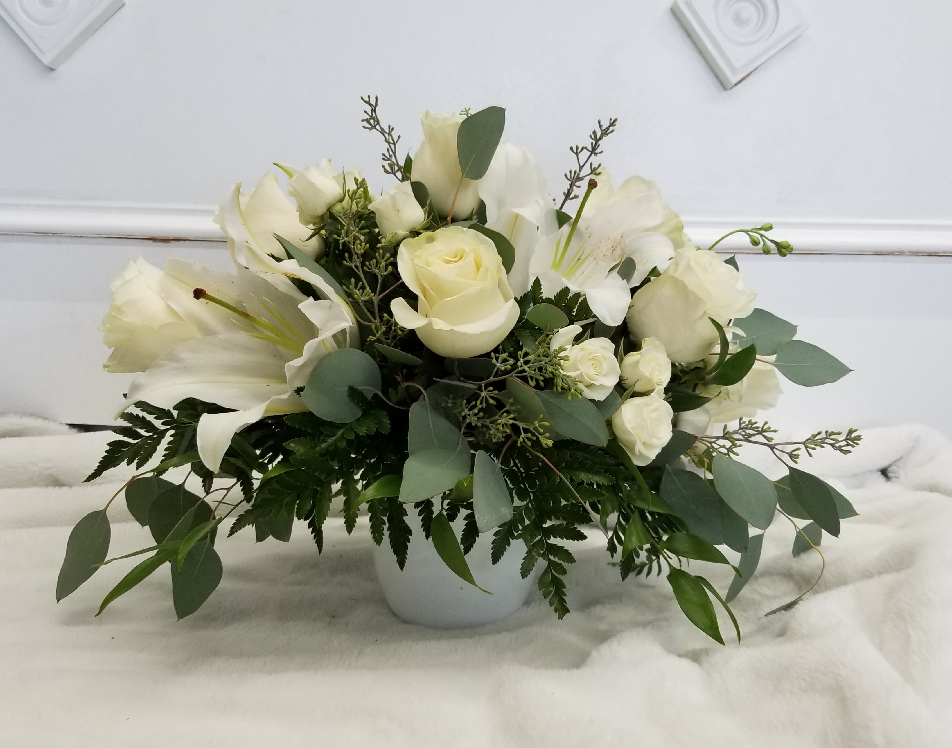 White roses and lilies arranged in a white vase
