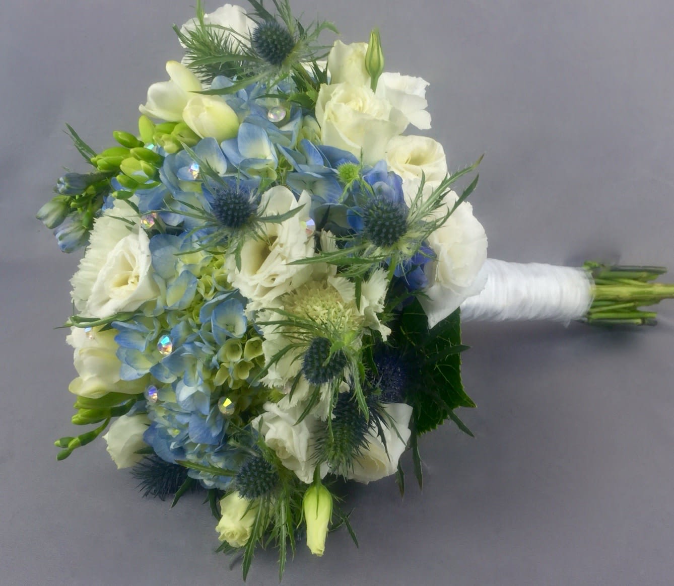 Blue and white bridal bouquet with spiky thistles and wrapped stems