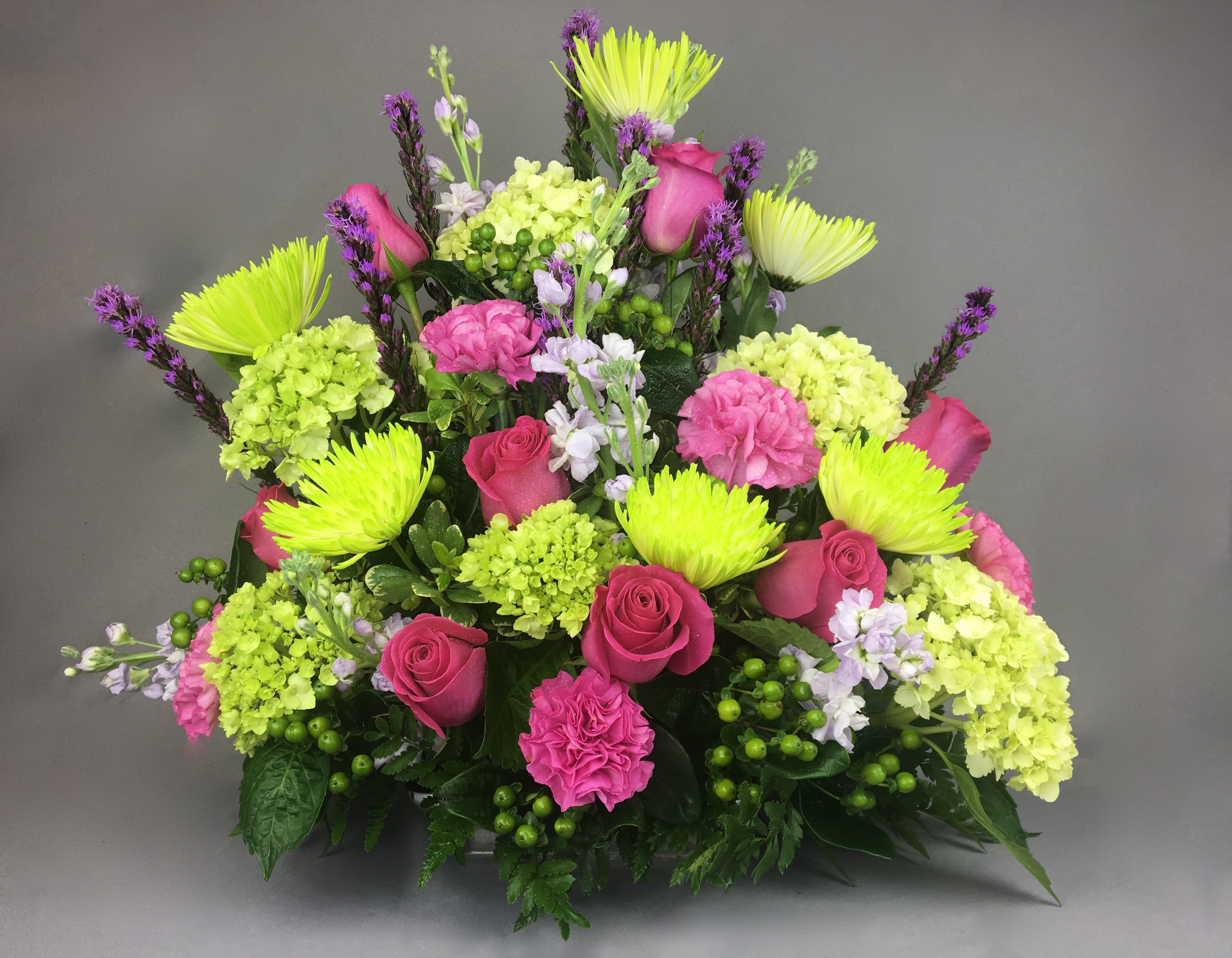 Bright pink roses and lime-green blooms in a mixed bouquet