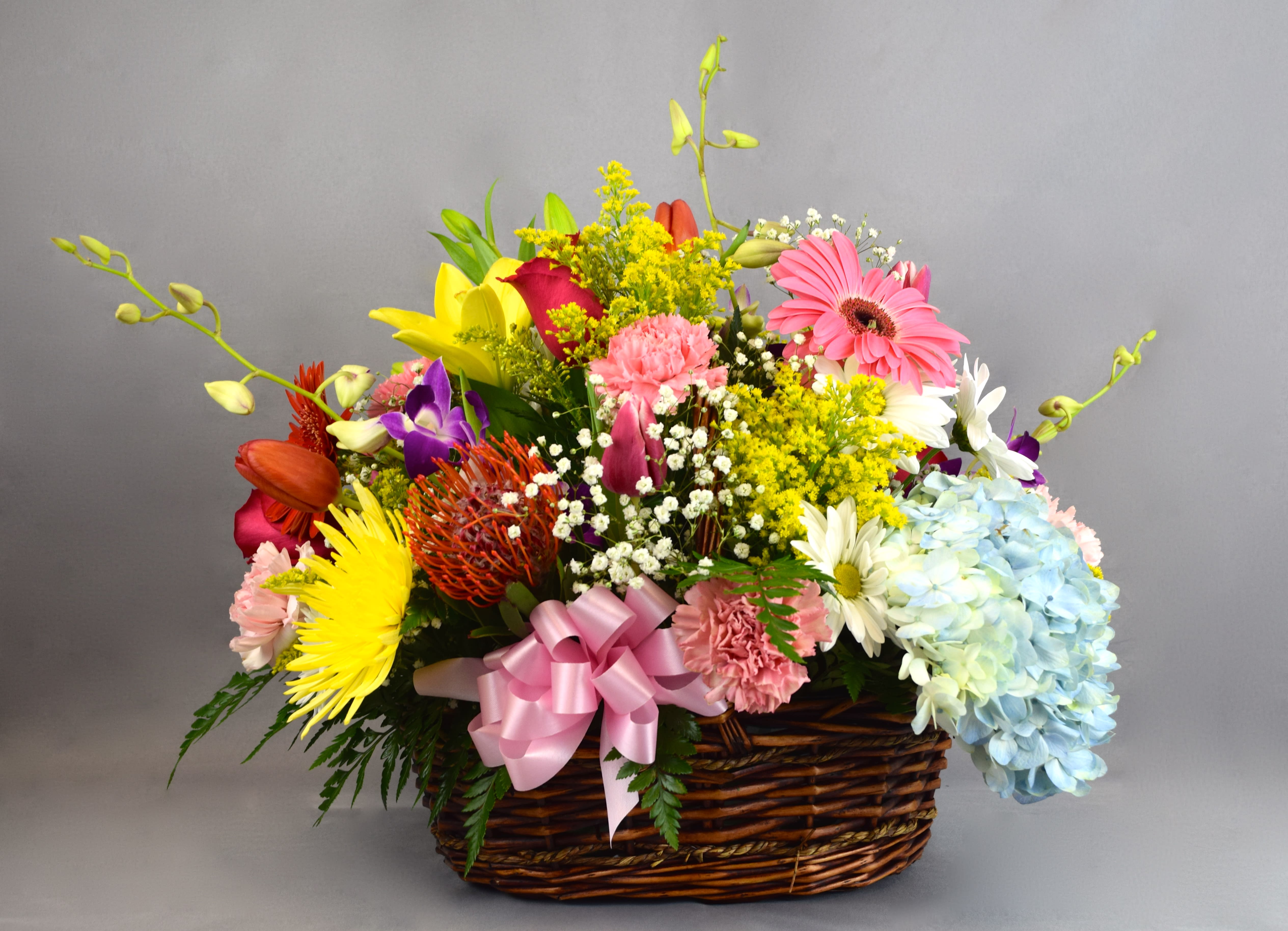Colorful mixed flower basket with a pink ribbon bow
