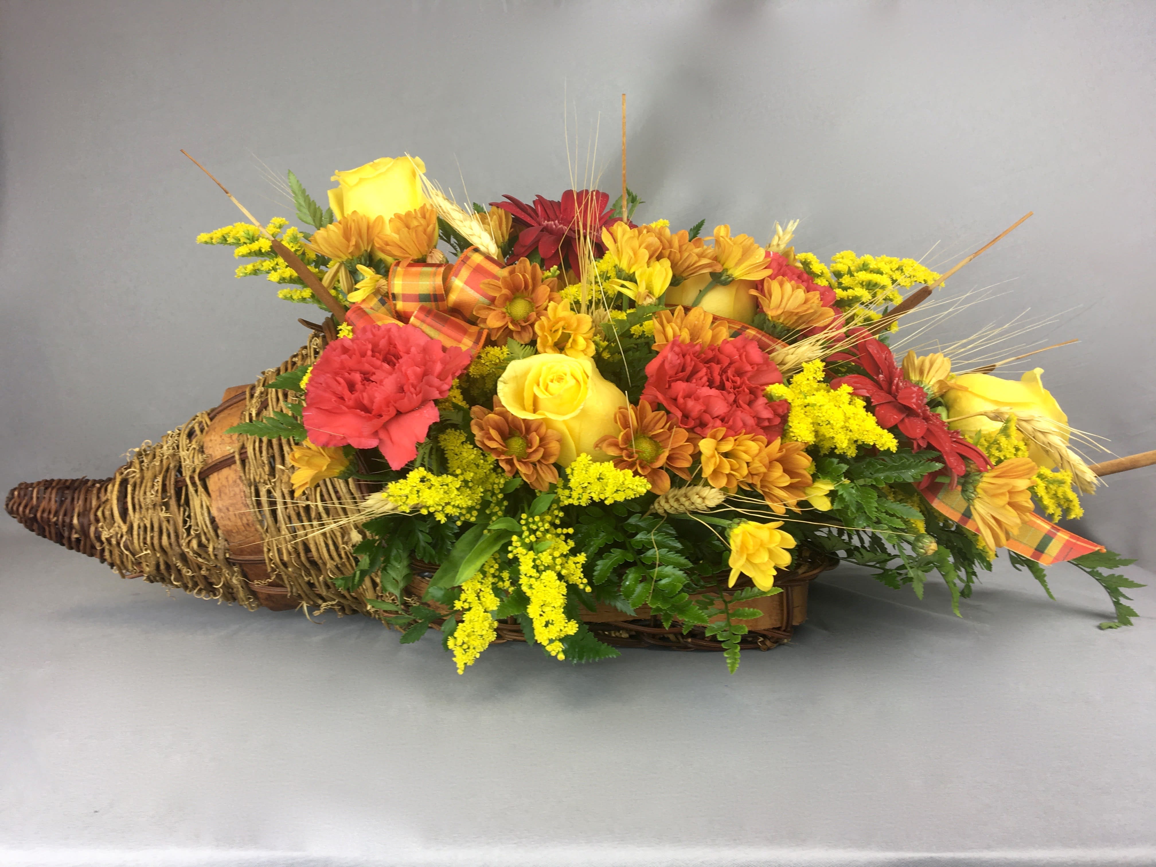 Basket arrangement with yellow roses, red carnations, and daisies