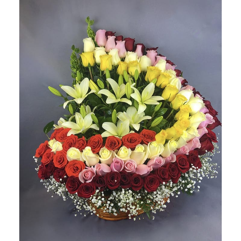 Large basket arrangement of multicolored roses and white lilies