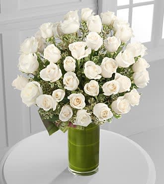 White roses arranged in a green glass vase
