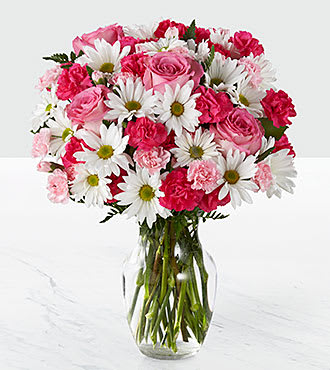 Pink roses and white daisies arranged in a clear glass vase