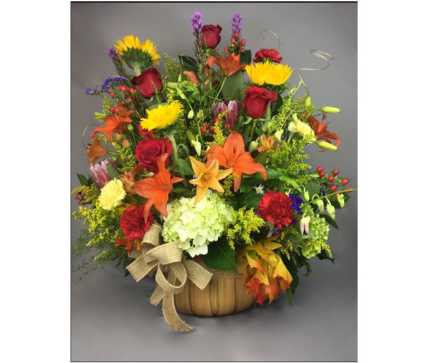 Mixed bouquet in a basket with red roses, lilies, and yellow blooms