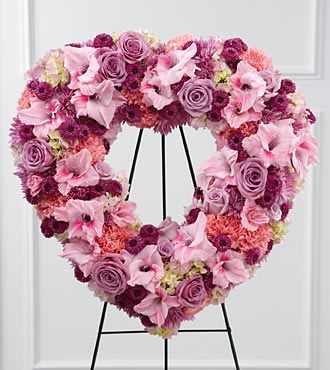 Heart-shaped floral wreath in pink and purple tones on a black stand