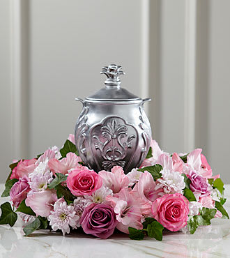 Pink floral arrangement surrounding a silver urn