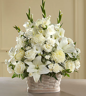 White floral arrangement in a woven basket with lilies and roses