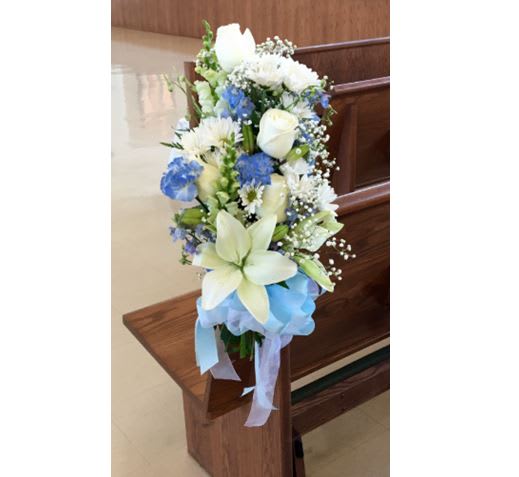 Tall blue and white floral arrangement with ribbon on a wooden stand