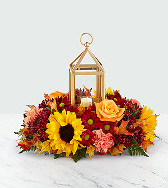 Autumn floral arrangement with sunflowers, roses, and a lantern centerpiece