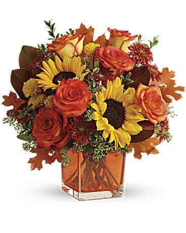 Autumn bouquet of roses and sunflowers in a square glass vase