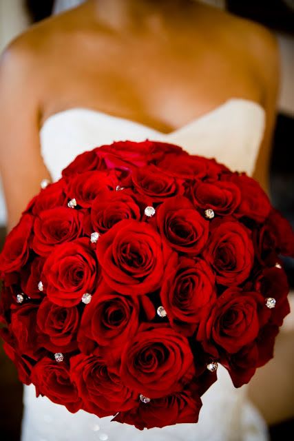 Bride holding a bouquet of red roses with jeweled accents