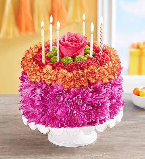 Round floral cake with candles and a pink rose on top