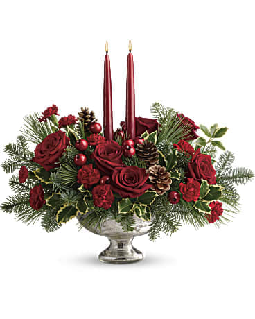 Red roses and holiday greenery in a silver bowl with two red candles
