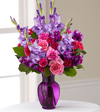 Pink and purple mixed bouquet in a purple glass vase