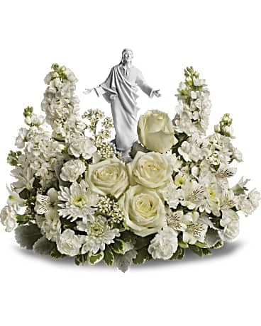White floral arrangement with a small religious statue in the center