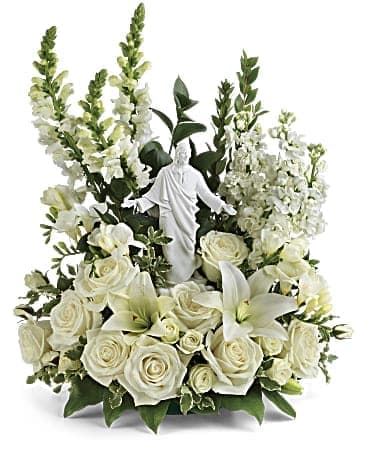 White floral arrangement with a small religious statue in the center