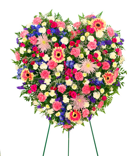 Heart-shaped standing spray of mixed pink, white, purple, and yellow flowers