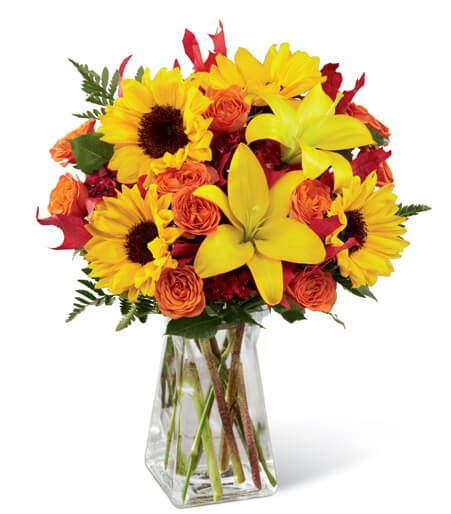Sunflowers and orange roses in a clear glass vase
