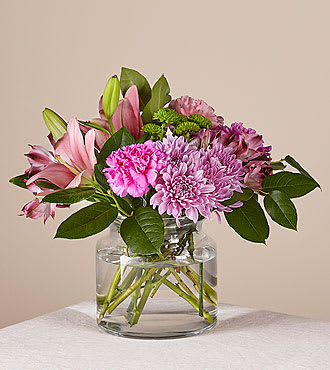 Pink and purple flowers arranged in a clear glass vase