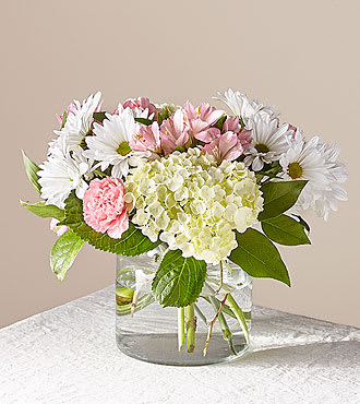 Pink and white flowers arranged in a clear glass vase