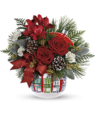 Red roses and lilies in a decorated glass vase with pinecones
