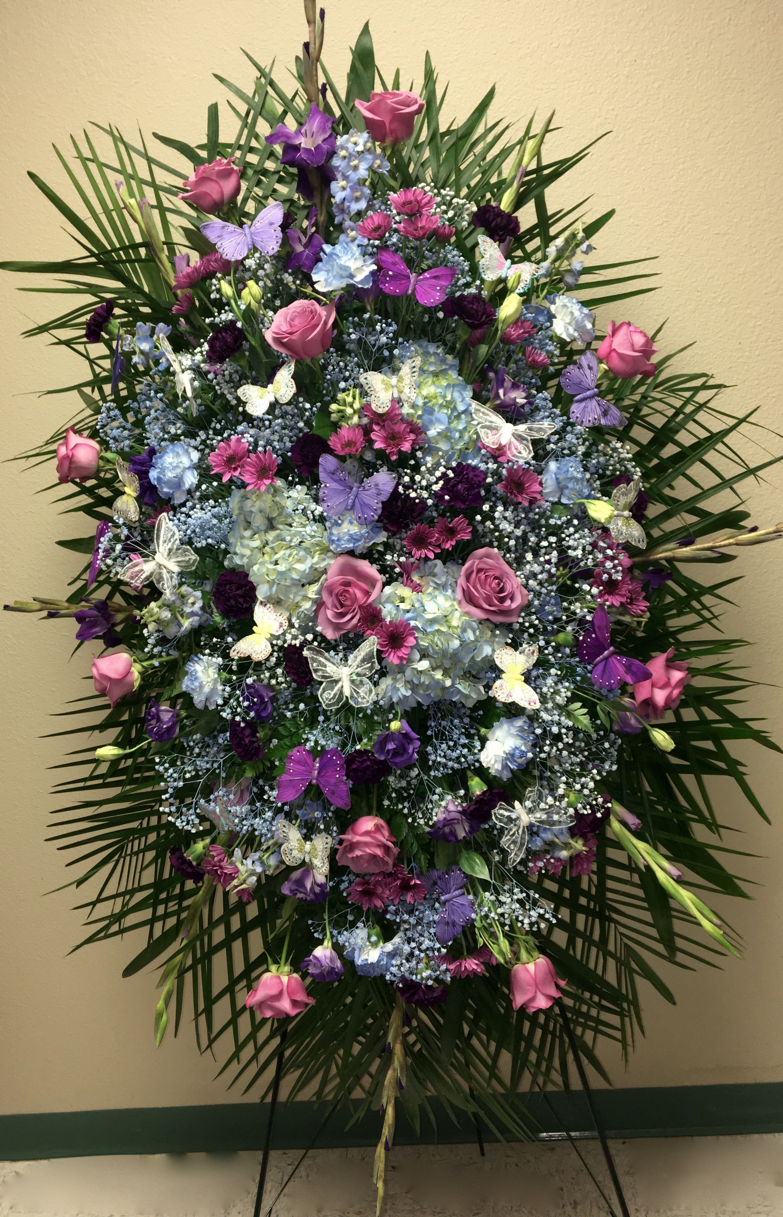 Large standing floral spray with pink and purple flowers and butterfly accents