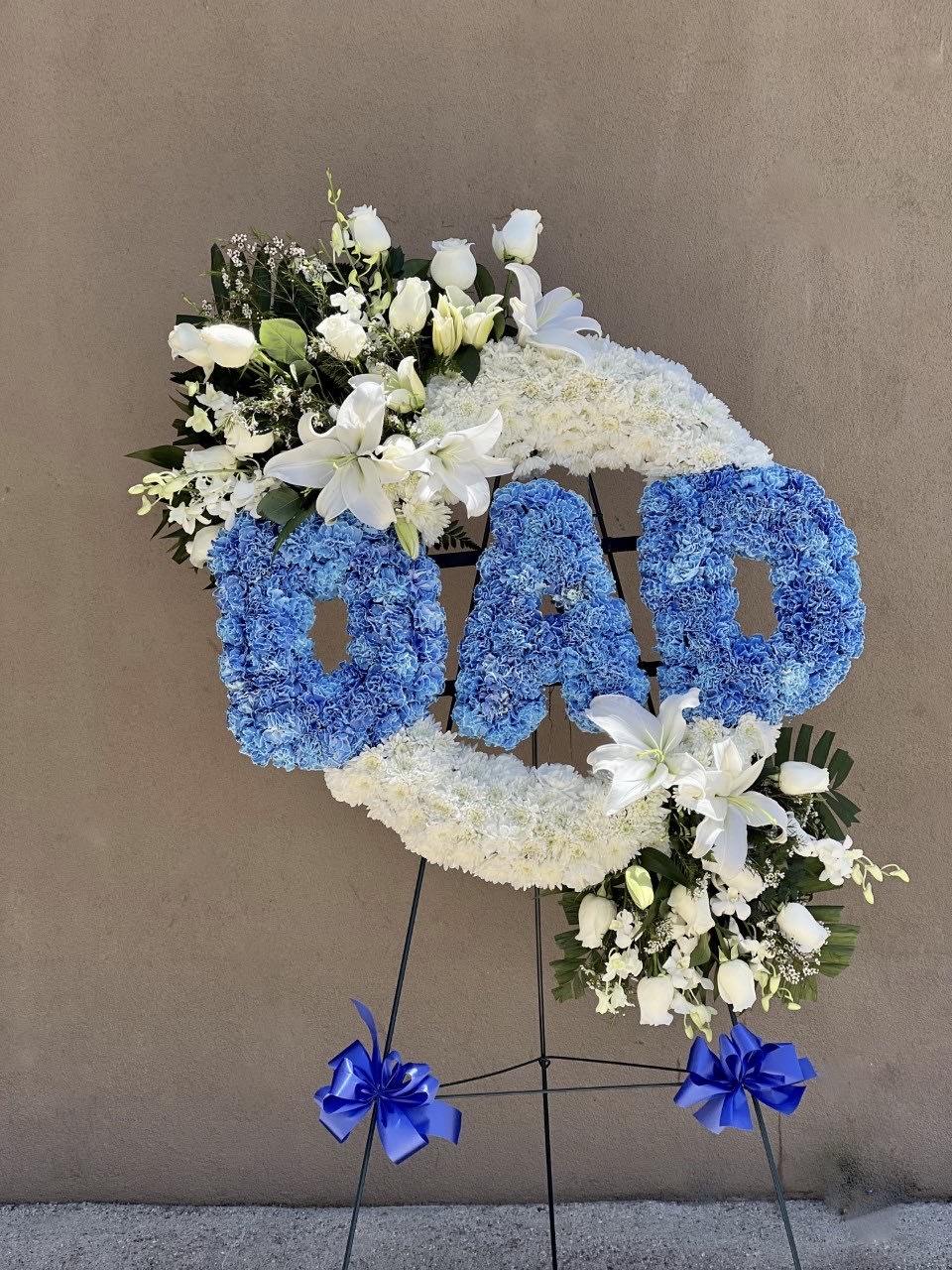 Floral standing tribute spelling DAD with blue and white flowers