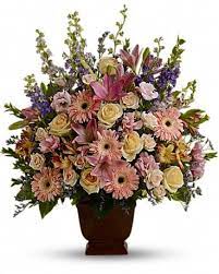 Mixed pink and cream flowers arranged in a brown urn vase