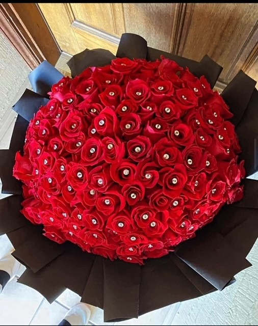 Large round bouquet of red roses wrapped in black paper