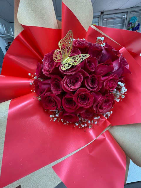 Bouquet of deep pink roses wrapped in bright red paper with a butterfly topper