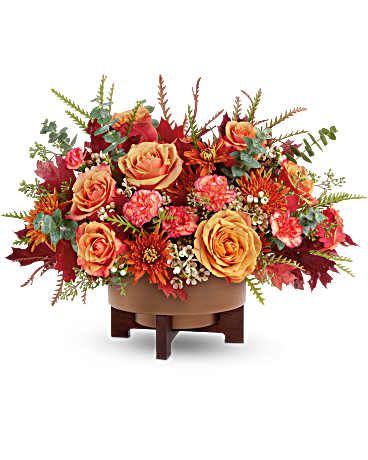 Autumn floral arrangement with orange roses in a low wooden stand