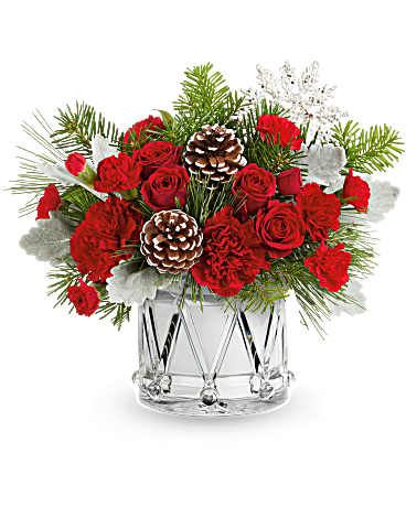 Red roses and carnations in a clear glass vase with pinecones