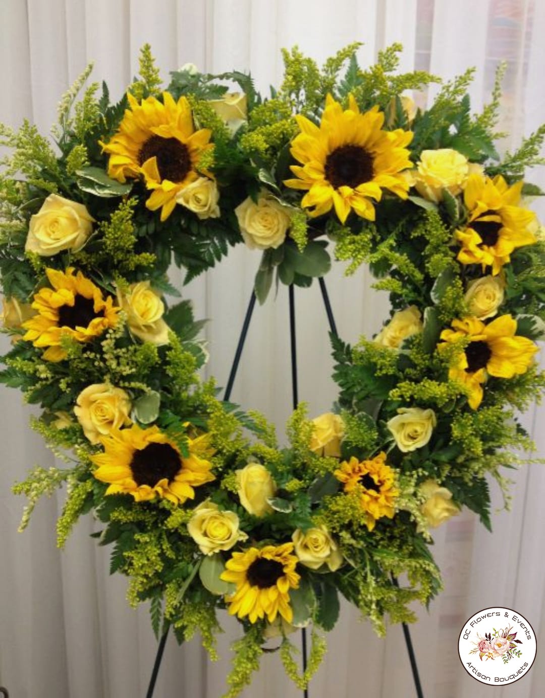 Standing wreath of yellow sunflowers and pale yellow roses on a metal easel