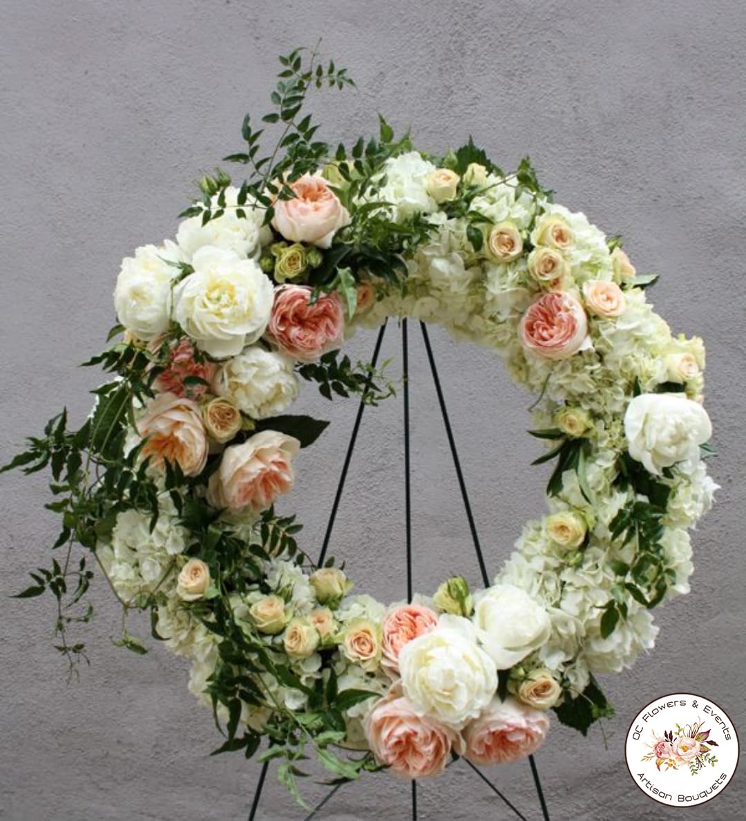 Standing wreath of white and peach roses and hydrangeas on a metal easel